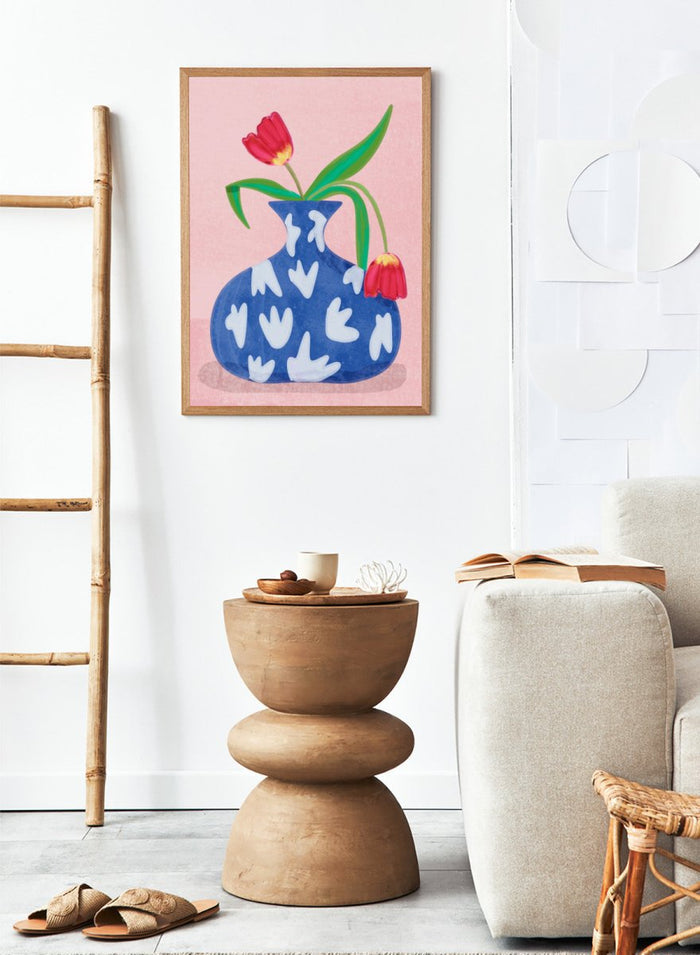 Blue vase with white abstract patterns and red tulips on a pink background. Tulip in Vase by Raissa Oltmanns fine art print featuring bold red tulip, blue patterned vase, modern contemporary floral wall decor poster.