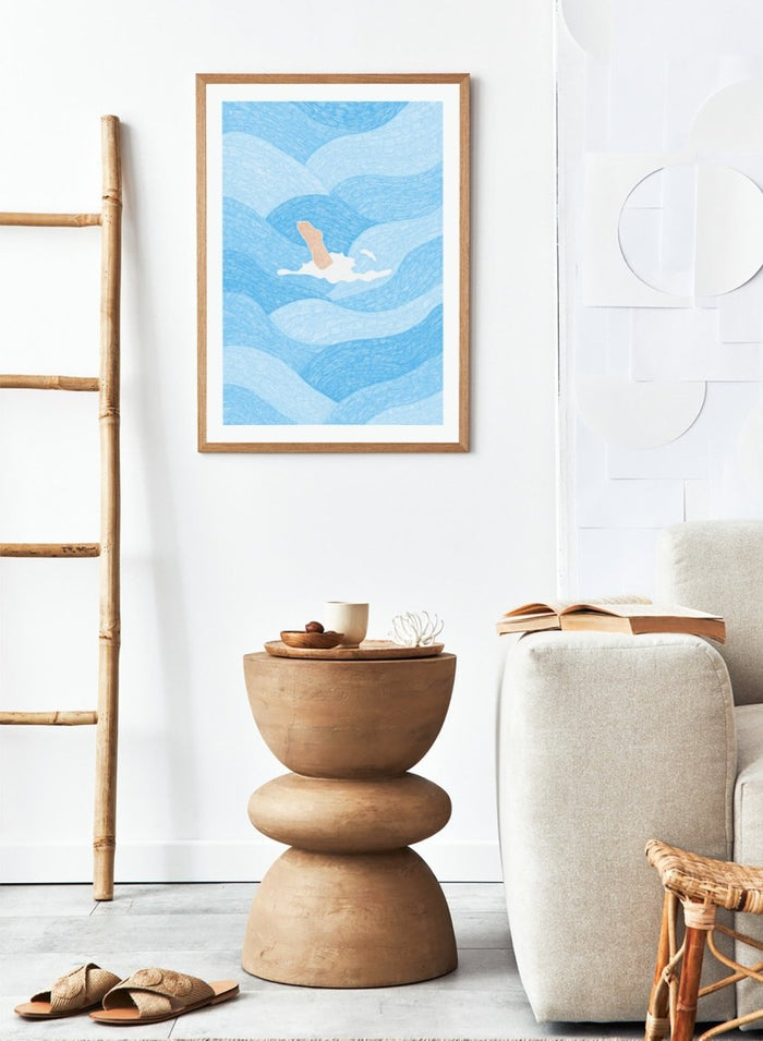 Illustration of a person swimming in blue water with a white border. Hand Reaching Blue Ocean by Rio Soléy is a modern coastal art print featuring swirling blue waves, minimalist illustration, playful design, and contemporary seaside charm.