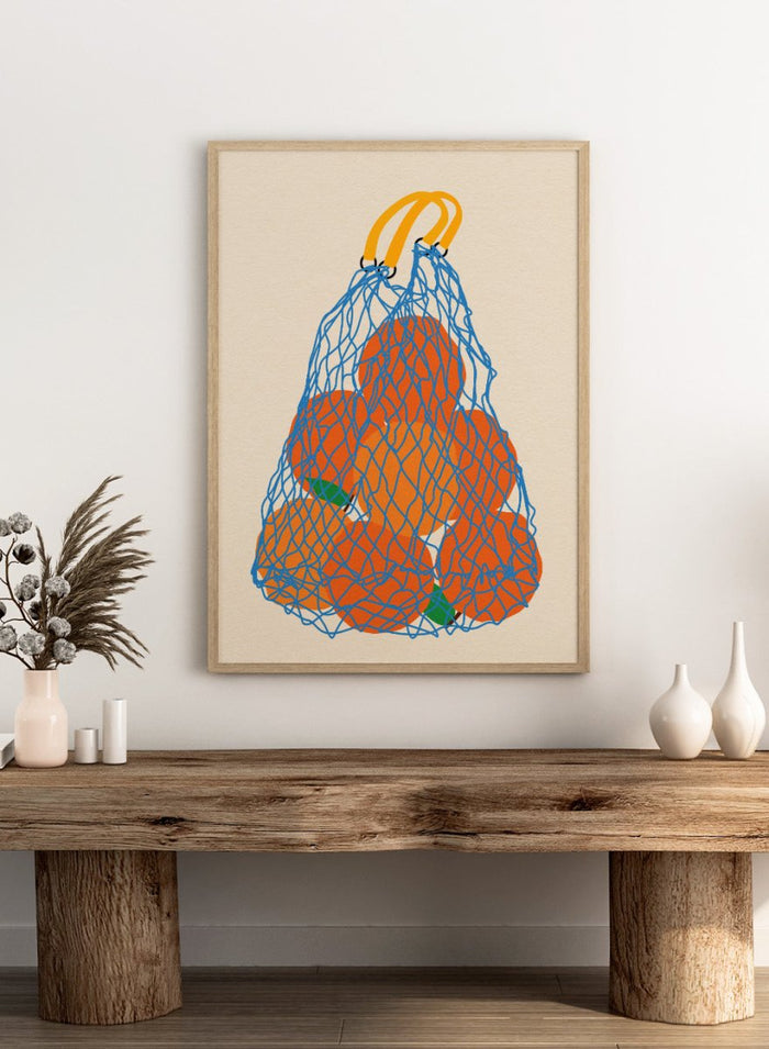 Blue mesh bag filled with orange fruits on a beige background. Oranges In a Net Bag by Rosi Feist is a modern minimalist fruit art print with bold color and Bauhaus-inspired graphic design. Officially licensed fine art poster with framing.