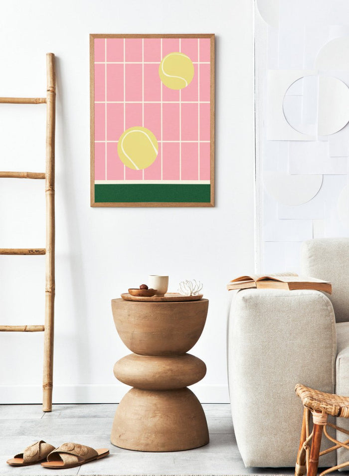 Two yellow tennis balls on a pink grid background with a green stripe at the bottom. Tennis Kitchen by Rosi Feist is a modern minimalist fine art print featuring oversized tennis balls on pink tile. Officially licensed wall poster with optional artisan framing.