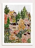 A framed art print featuring a hand-drawn, stylized landscape of a hillside village with beige buildings, brown roofs, and dense trees in green, yellow, orange, and red tones. Shop Autumn Hillside Village by Rushati Chowdhury, a colorful autumn landscape art print with hillside homes, winding steps, dense trees, and warm fall tones.