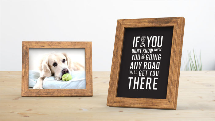 Rustic picture frame displaying a dog with a green ball and a motivational quote on a light wooden table.