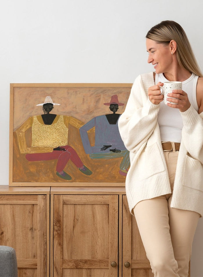 Framed artwork of two people sitting on a bench with a plain background. Still, Together by Studio IMO (Ibi Meier-Oruitemeka) is a modern figurative art print with two seated figures in a contemporary wall poster design.