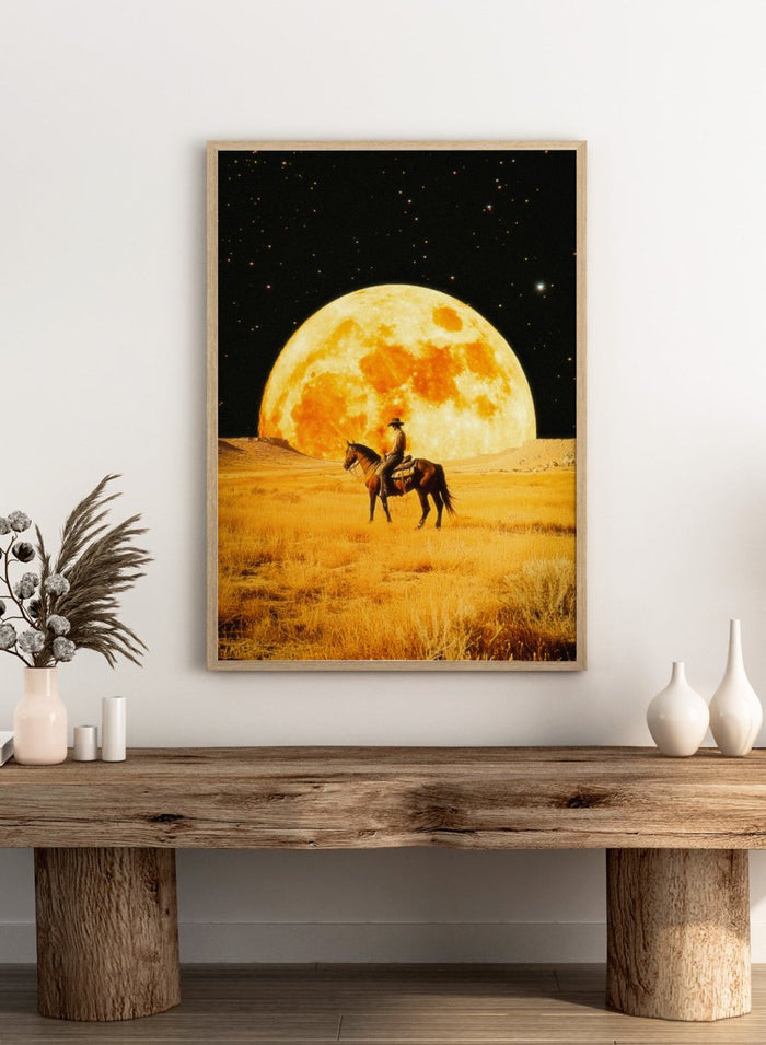 Cowboy on horseback under a large moon in a desert landscape. Lunar Cowboy by Taudalpoi surreal western cowboy moon art print with giant glowing moon and desert landscape, retro cosmic collage poster wall art.