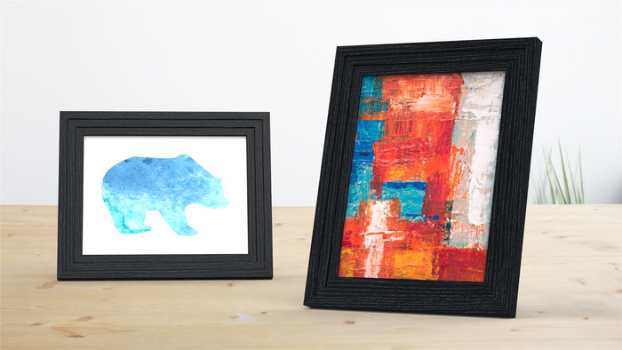 Black picture and poster frame displaying an abstract art piece and a blue bear illustration.